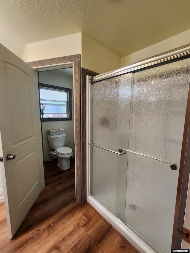 828 Fort St, Buffalo, WY 82834 - full bathroom featuring wood finished floors, a shower with shower door, and a textured ceiling