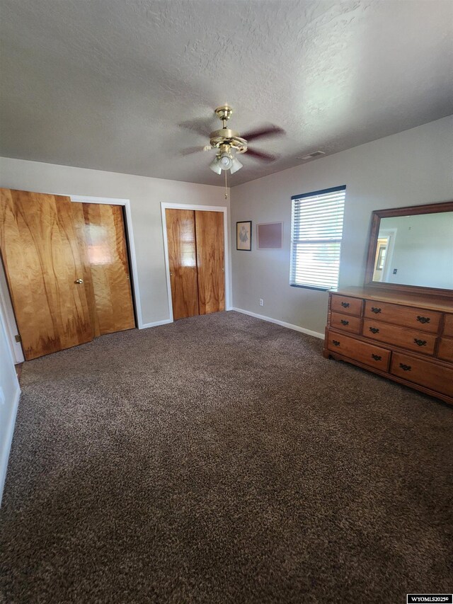 828 Fort St, Buffalo, WY 82834 - unfurnished bedroom featuring multiple closets, carpet, a textured ceiling, and ceiling fan