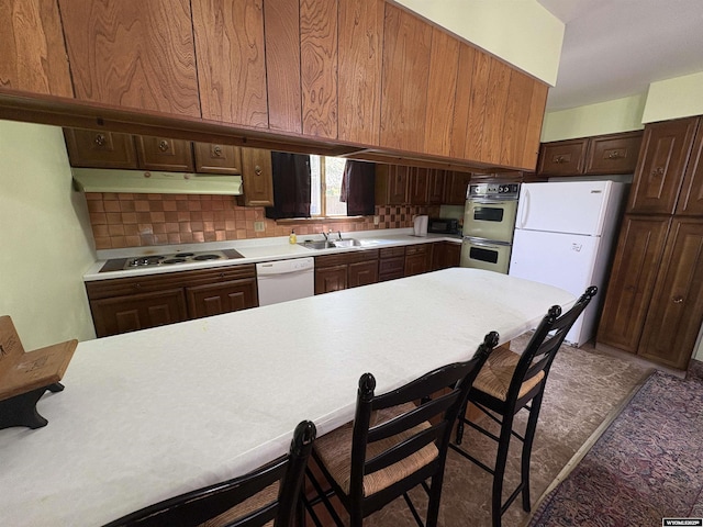 1501 N Federal Blvd, Riverton, WY 82501 - kitchen with white appliances, under cabinet range hood, light countertops, backsplash, and dark brown cabinetry
