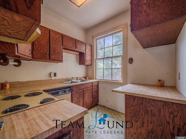 719 E 4th St, Casper, WY 82601 - kitchen with light countertops, range hood, dishwasher, brown cabinetry, and stovetop