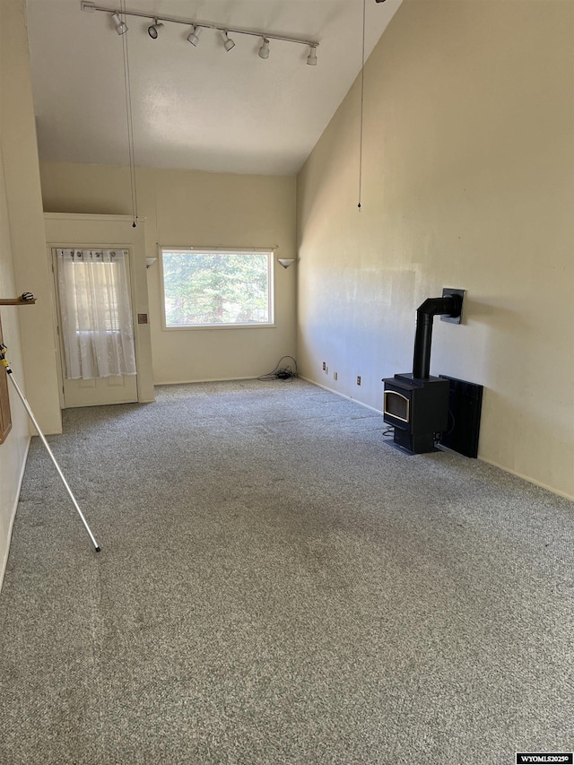 133 Shady Ln, Evanston, WY 82930 - unfurnished living room featuring track lighting, a wood stove, and carpet