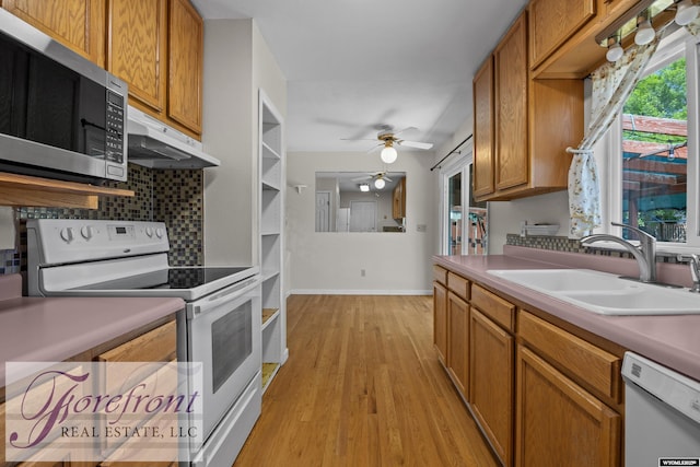 2240 E 17th St, Casper, WY 82609 - kitchen with white appliances, under cabinet range hood, backsplash, ceiling fan, and light wood finished floors