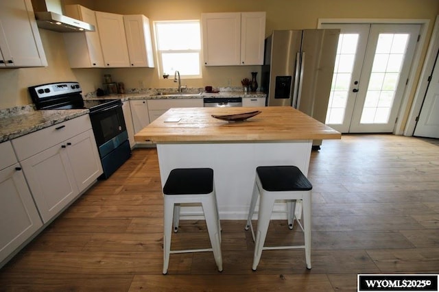 380 S-A Rd, Morrill, NE 69358 - kitchen featuring stainless steel appliances, wall chimney range hood, a breakfast bar, butcher block counters, and wood-type flooring