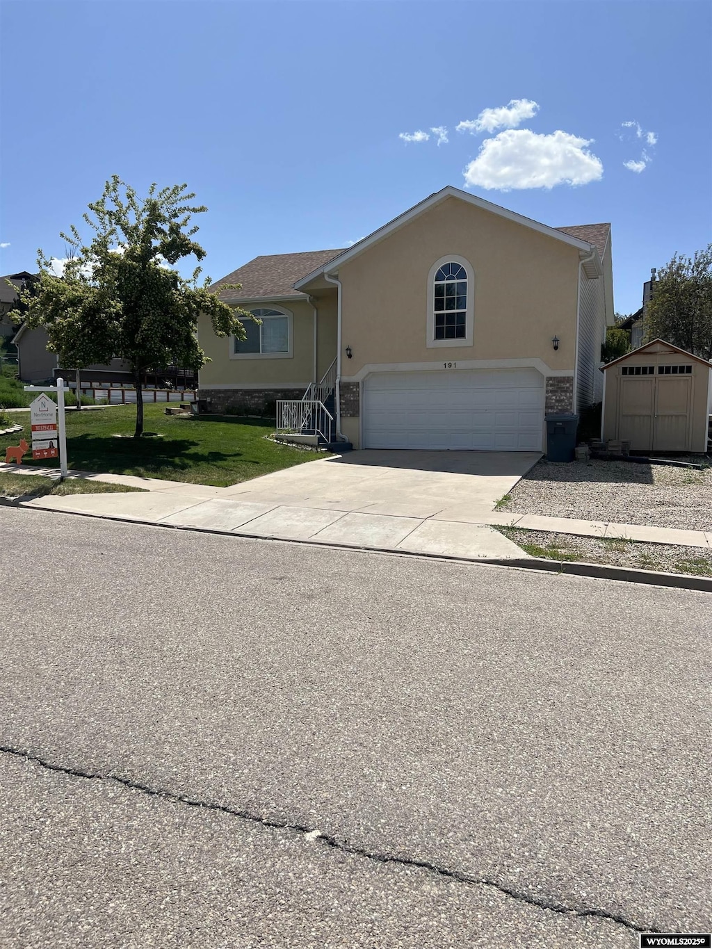 191 Ridge Ln, Evanston, WY 82930 - view of front of home with an attached garage, a shed, concrete driveway, a front yard, and stucco siding