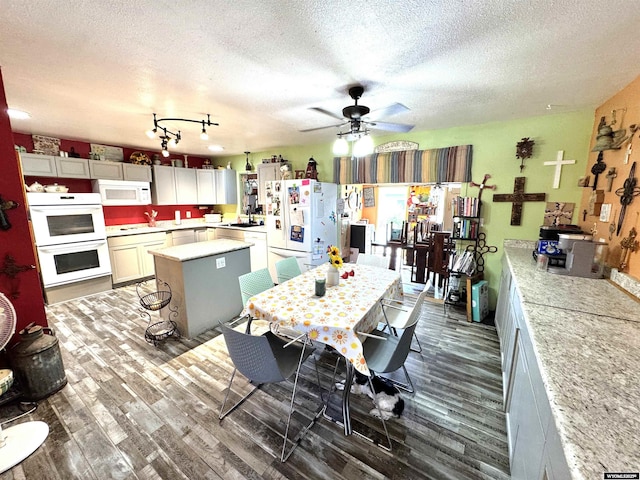 327 S Iowa Ave, Guernsey, WY 82214 - kitchen with white appliances, wood finished floors, a textured ceiling, light countertops, and a kitchen island