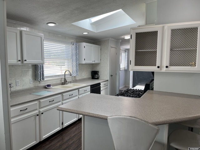 703 Randolph St, Rock Springs, WY 82901 - kitchen featuring a skylight, black dishwasher, white cabinets, light countertops, and a peninsula