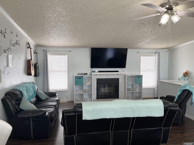 703 Randolph St, Rock Springs, WY 82901 - living area with ornamental molding, dark wood-style flooring, a textured ceiling, a ceiling fan, and a tile fireplace