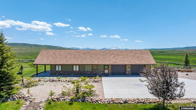 966 Mill Creek Rd, Evanston, WY 82930 - view of front facade with a garage, driveway, stone siding, roof with shingles, and a mountain view