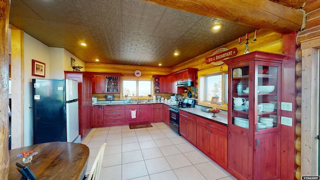 11 Heather Ln, Lander, WY 82520 - kitchen featuring black gas range oven, freestanding refrigerator, dark brown cabinets, ventilation hood, and light tile patterned flooring