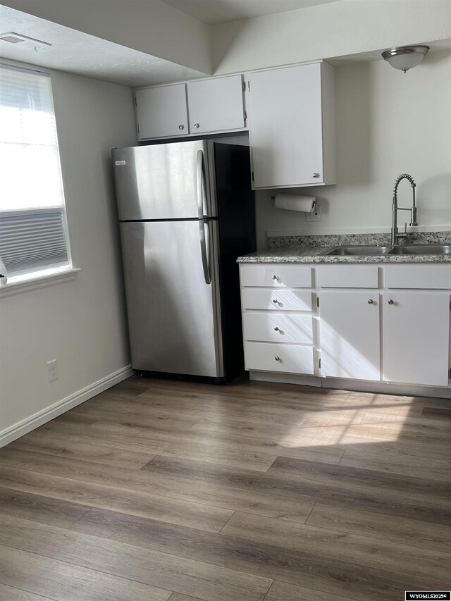 721 Sioux, Evanston, WY 82930 - kitchen with freestanding refrigerator, wood finished floors, white cabinets, and light stone countertops