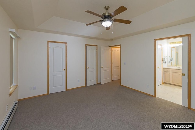 2215 Silver Creek Dr, Rock Springs, WY 82901 - unfurnished bedroom featuring a baseboard heating unit, carpet floors, a tray ceiling, connected bathroom, and two closets