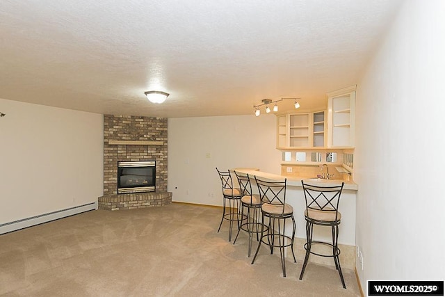 2215 Silver Creek Dr, Rock Springs, WY 82901 - dining area featuring light carpet, bar with sink, a fireplace, baseboard heating, and a textured ceiling