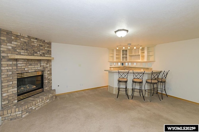 2215 Silver Creek Dr, Rock Springs, WY 82901 - kitchen featuring carpet, open shelves, a breakfast bar area, and a fireplace