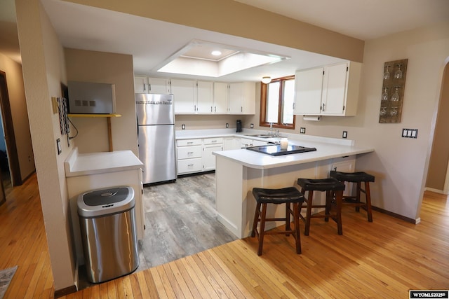 609 Klondike Dr, Buffalo, WY 82834 - kitchen with freestanding refrigerator, a peninsula, light wood-style flooring, and white cabinets