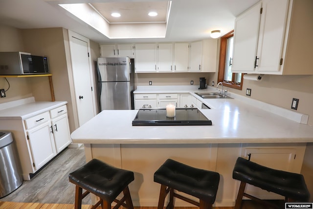 609 Klondike Dr, Buffalo, WY 82834 - kitchen with freestanding refrigerator, a peninsula, light wood-style floors, light countertops, and white cabinets