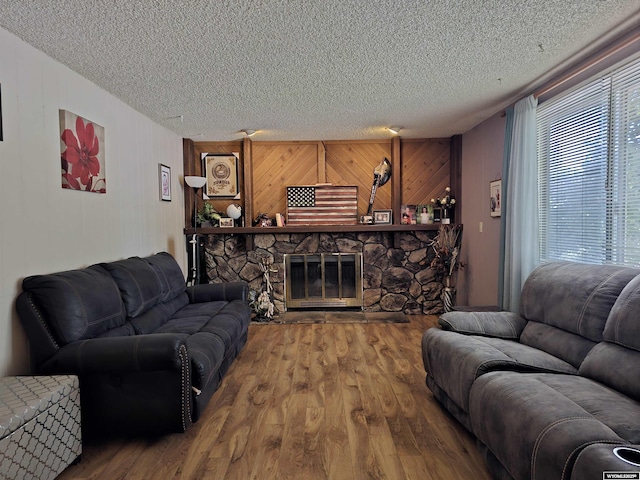 313 Cottonwood St, Evanston, WY 82930 - living room with a textured ceiling, wood finished floors, a stone fireplace, and wooden walls