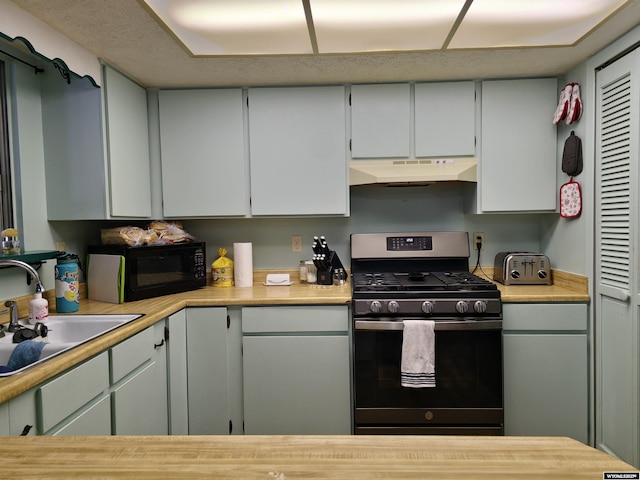 313 Cottonwood St, Evanston, WY 82930 - kitchen featuring stainless steel gas range, black microwave, under cabinet range hood, and light countertops