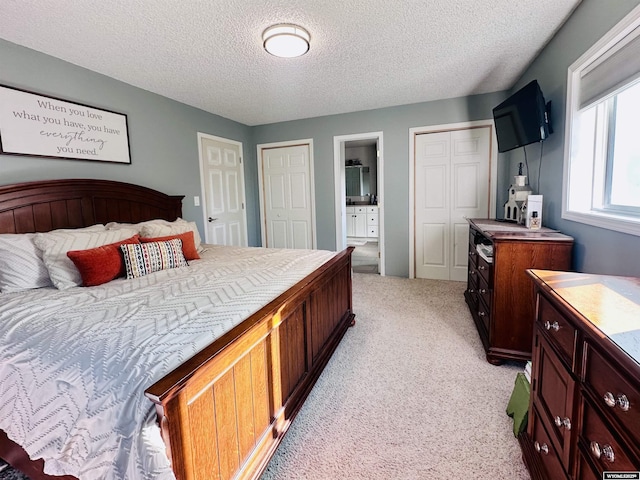 1542 Cloud Peak Dr, Worland, WY 82401 - bedroom with light colored carpet, a textured ceiling, multiple closets, and ensuite bath