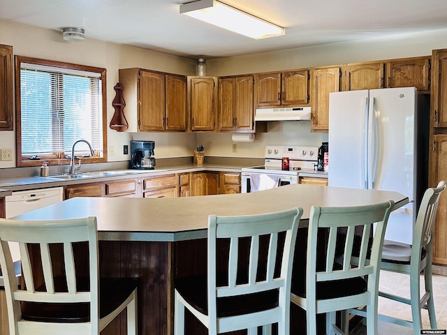 1542 Cloud Peak Dr, Worland, WY 82401 - kitchen featuring white appliances, under cabinet range hood, light countertops, and a breakfast bar area