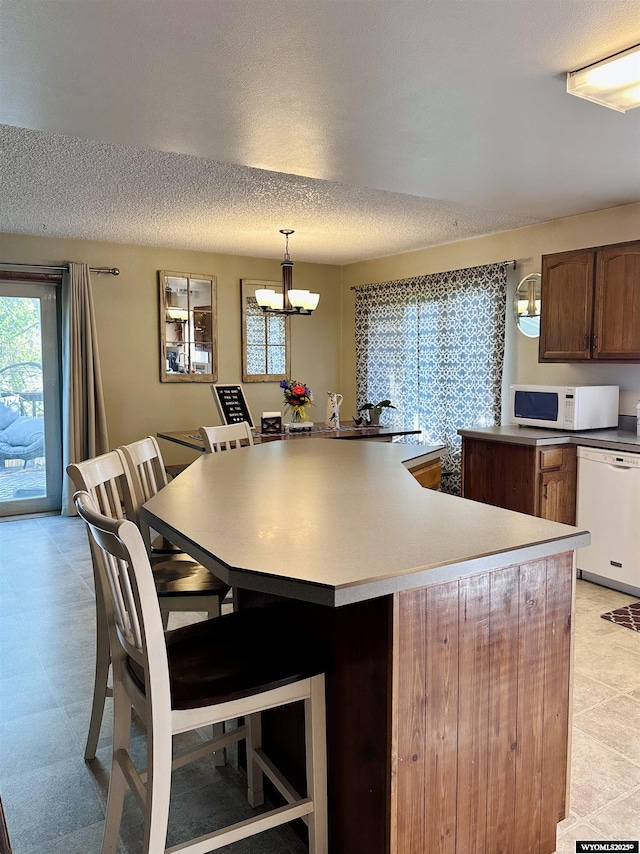 1542 Cloud Peak Dr, Worland, WY 82401 - kitchen featuring white appliances, a chandelier, hanging light fixtures, a textured ceiling, and a center island