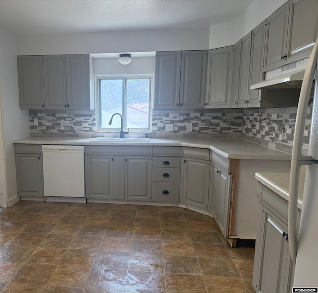 524 E Murray St, Rawlins, WY 82301 - kitchen featuring dishwasher, under cabinet range hood, gray cabinets, and backsplash