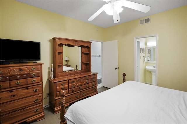 bedroom featuring a textured ceiling, sink, ceiling fan, and ensuite bath