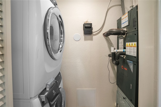 washroom featuring stacked washer / drying machine and heating unit