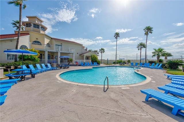 community pool with a patio and fence