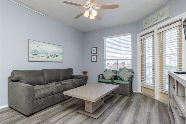 living room with light wood-type flooring, ceiling fan, and baseboards