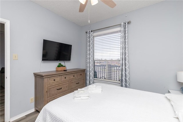 bedroom with ceiling fan, a textured ceiling, baseboards, and wood finished floors