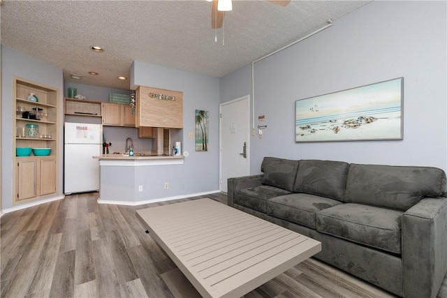 living room featuring recessed lighting, ceiling fan, a textured ceiling, light wood-type flooring, and baseboards