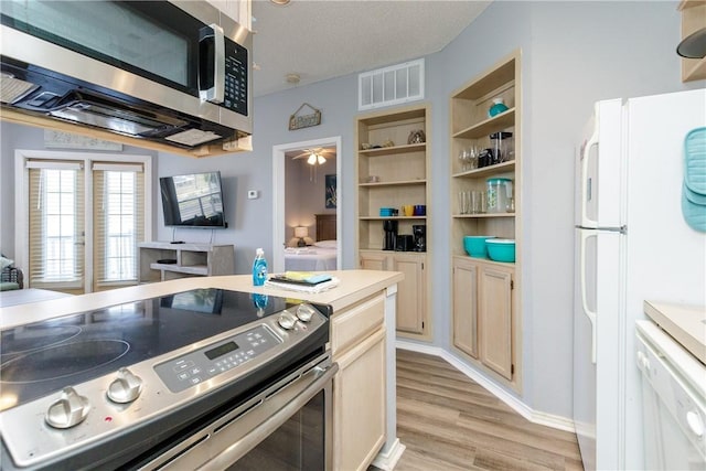 kitchen with light wood finished floors, visible vents, a ceiling fan, appliances with stainless steel finishes, and light countertops