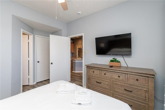 bedroom with a textured ceiling, ceiling fan, and wood finished floors