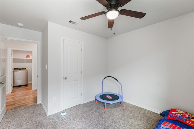 unfurnished bedroom featuring light carpet, ceiling fan, and washer / dryer