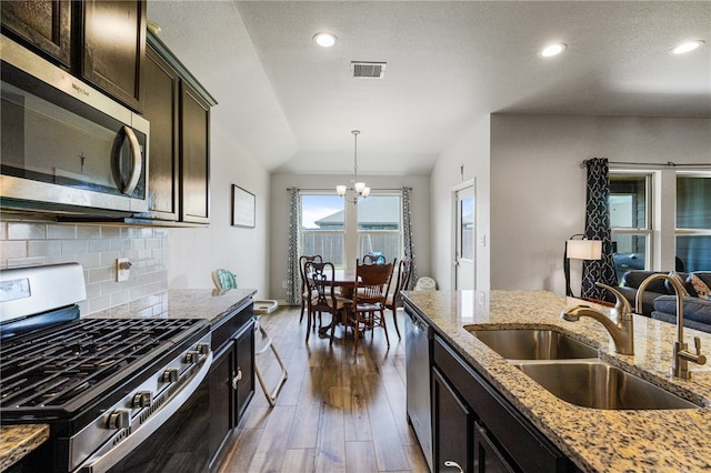 kitchen featuring lofted ceiling, light stone countertops, appliances with stainless steel finishes, and dark hardwood / wood-style flooring