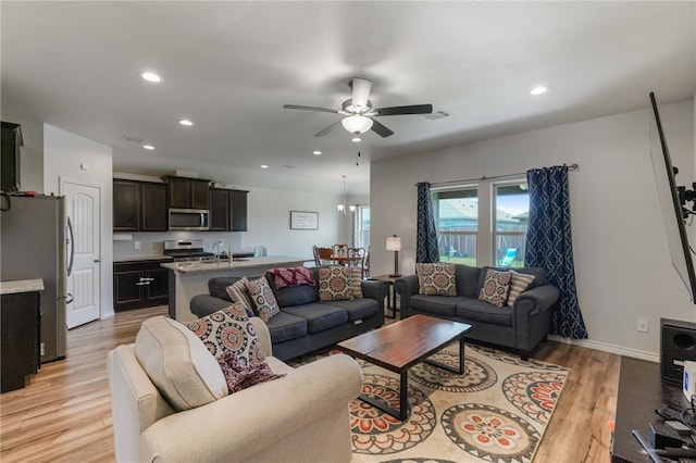 living room with light hardwood / wood-style floors, ceiling fan, and sink