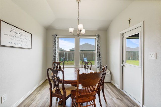 dining room featuring an inviting chandelier, light hardwood / wood-style flooring, and lofted ceiling