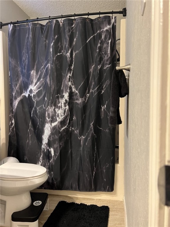 bathroom with hardwood / wood-style floors, toilet, and a textured ceiling