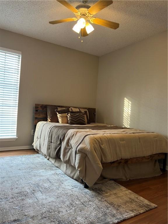 bedroom featuring ceiling fan, hardwood / wood-style floors, and a textured ceiling