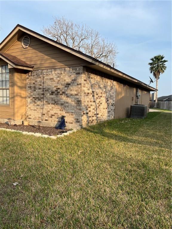 view of side of home featuring cooling unit and a lawn