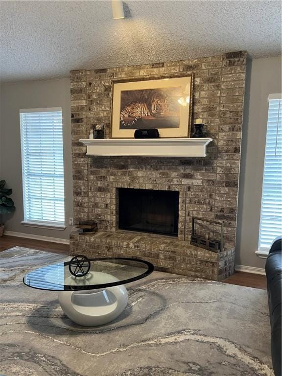 sitting room with hardwood / wood-style flooring, a fireplace, a textured ceiling, and a wealth of natural light