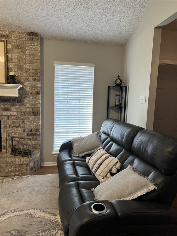 living room featuring wood-type flooring, a textured ceiling, and a fireplace