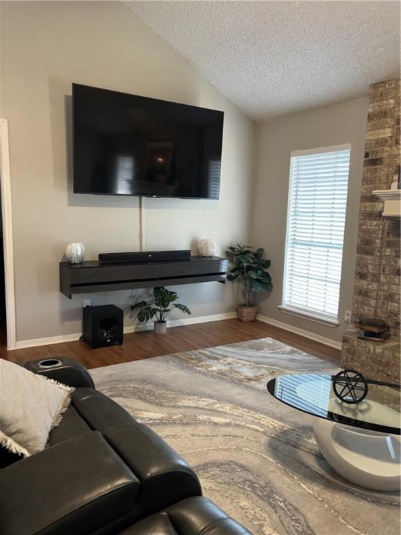 living room featuring hardwood / wood-style flooring, vaulted ceiling, and a textured ceiling