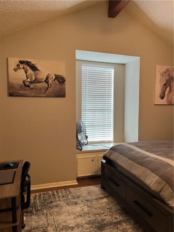 bedroom featuring vaulted ceiling with beams, hardwood / wood-style floors, and a textured ceiling