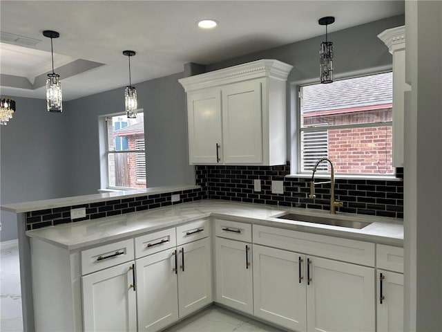 kitchen with sink, tasteful backsplash, decorative light fixtures, kitchen peninsula, and white cabinets