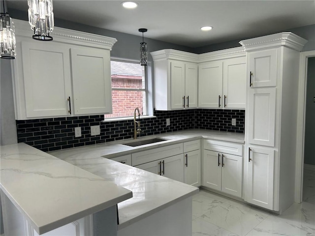 kitchen with sink, decorative light fixtures, kitchen peninsula, white cabinets, and backsplash