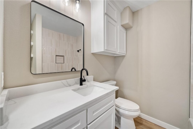 bathroom featuring baseboards, toilet, vanity, and walk in shower