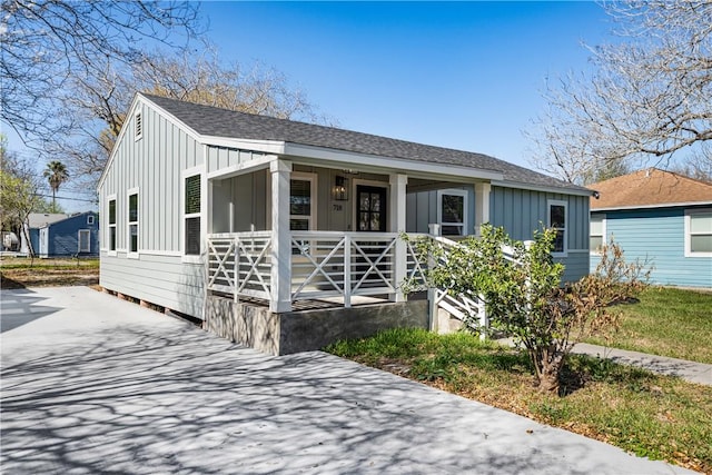 view of front facade with covered porch, board and batten siding, and roof with shingles