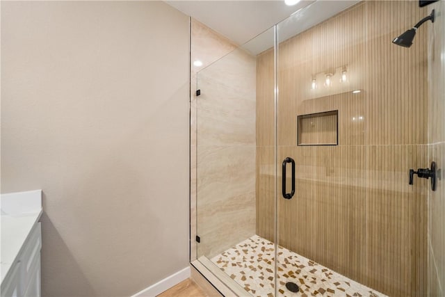 full bath featuring vanity, a shower stall, and baseboards