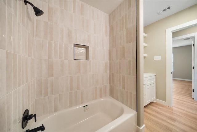 bathroom with visible vents, washtub / shower combination, baseboards, and wood finished floors